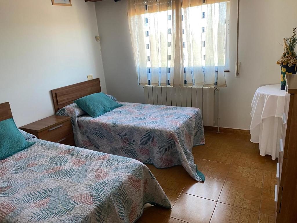 Habitación con 2 camas, mesa y ventana en Casa Portomeiro en San Román
