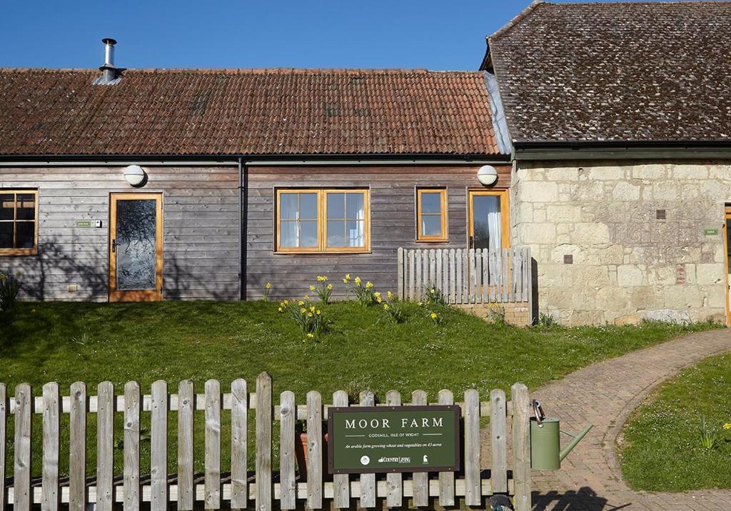 a house with a wooden fence in front of it at The Grainstore at Moor Farm in Godshill