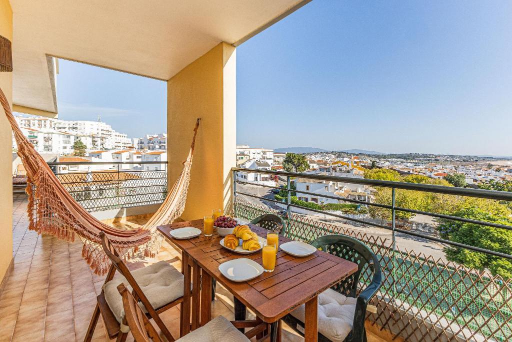 Un balcón con una mesa de madera, sillas y una hamaca. en Lagos Sea View by Algarve Golden Properties en Lagos