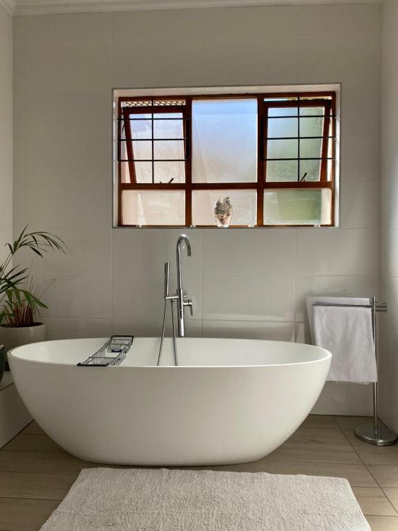 uma banheira branca na casa de banho com uma janela em Modern Serene 3 Bedroom Villa em Joanesburgo