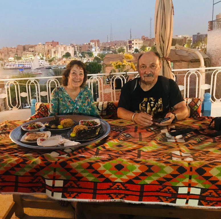 a man and a woman sitting at a table with food at Gamal Robob Nubian Guest House in Aswan
