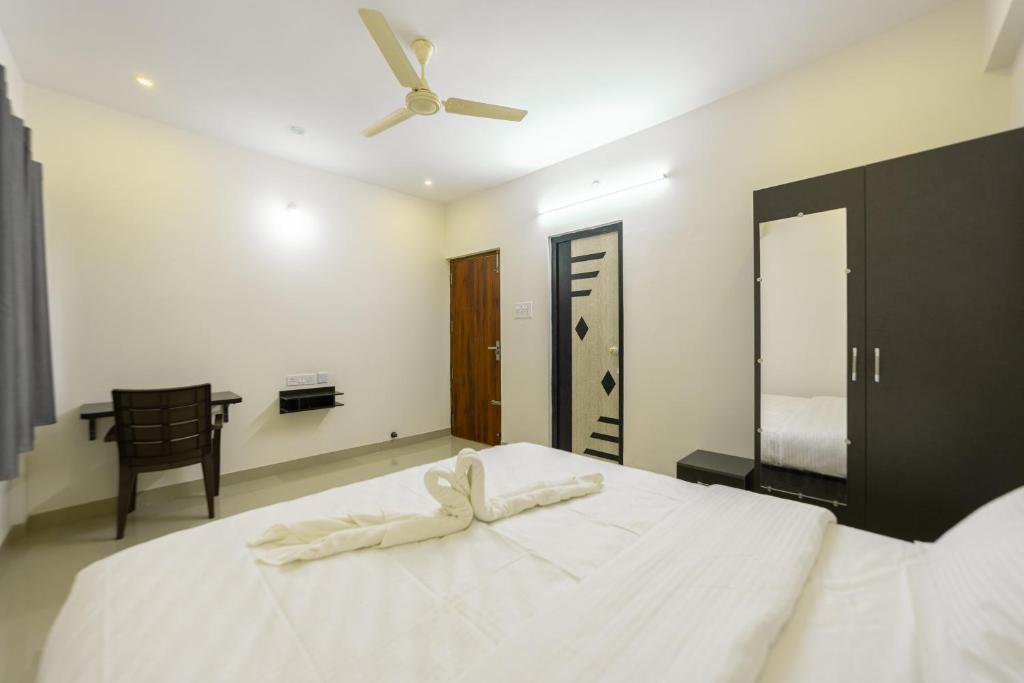 a bedroom with a large white bed with a ceiling fan at Fortune Inn in Erode