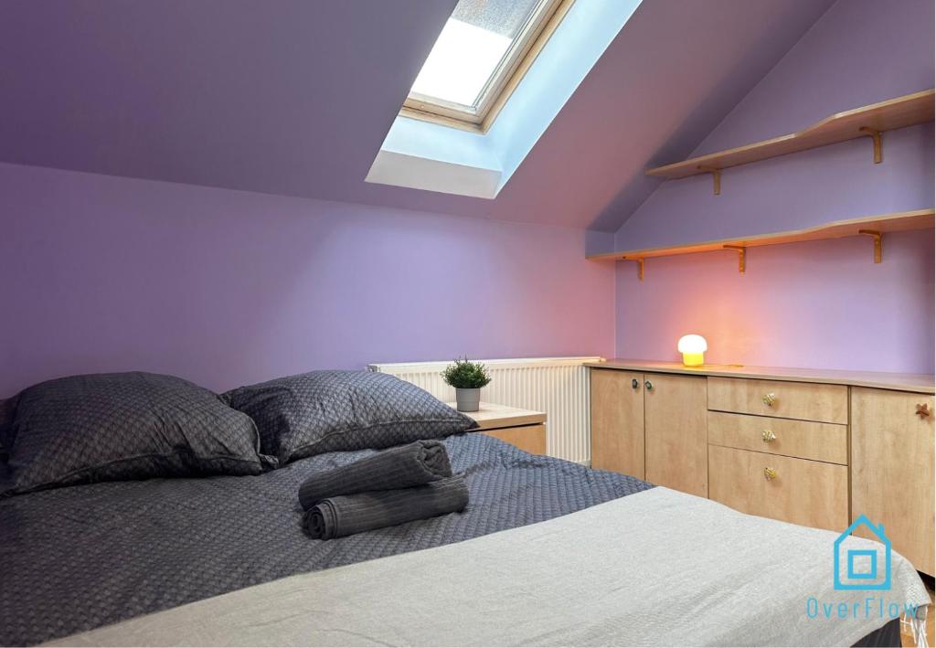- une chambre avec des murs violets, un lit et une lucarne dans l'établissement Purple Room, à Gdańsk
