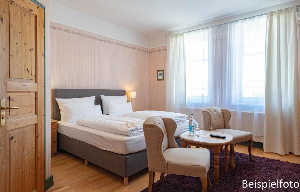 une chambre d'hôtel avec un lit, une table et des chaises dans l'établissement Logierhaus am Denkmal, à Norderney