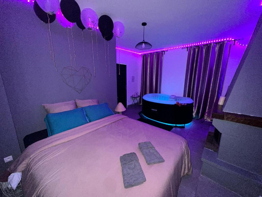 um quarto com uma cama e uma banheira com luzes roxas em Love Room avec Jacuzzi proche Paris et Roissy CDG em Persan