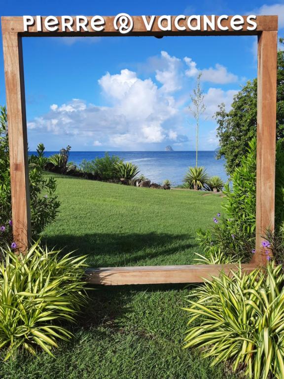 um sinal para um jardim com o oceano ao fundo em Studio privé dans un village de vacances em Sainte-Luce