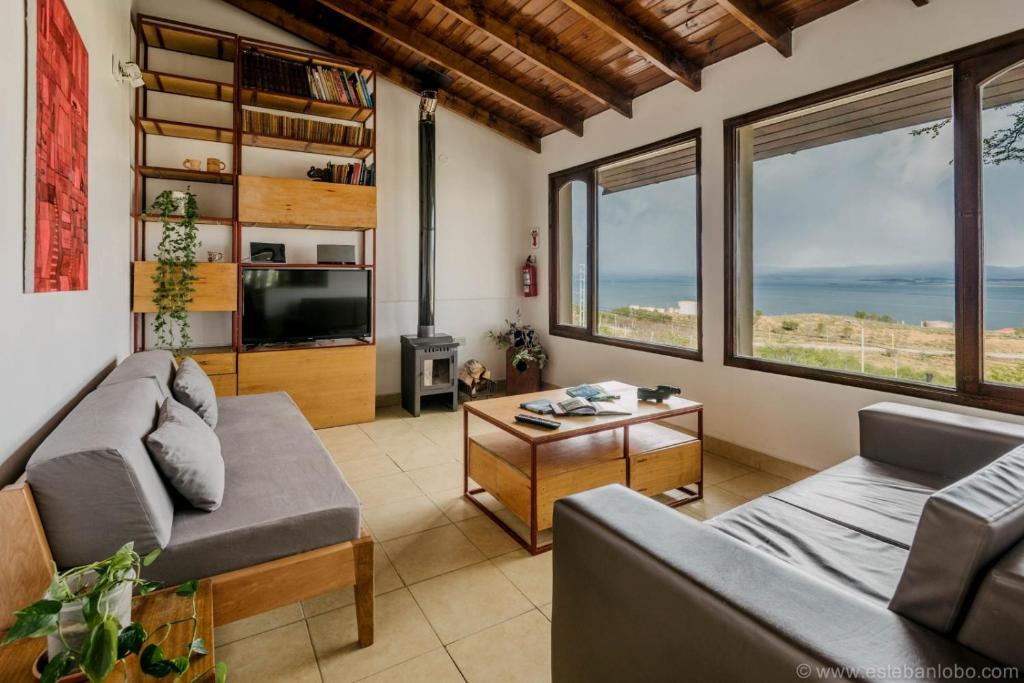 a living room with a couch and a tv and windows at Casa Bellavista Ushuaia in Ushuaia