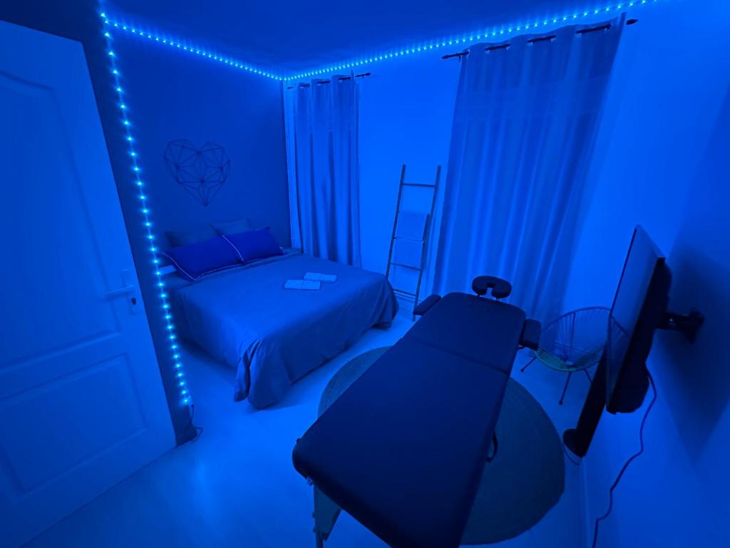 ein blaues Zimmer mit einem Bett und einem TV in der Unterkunft Guest Room Bien-être et cosy près de Paris, Roissy CDG et du village Olympique in Persan