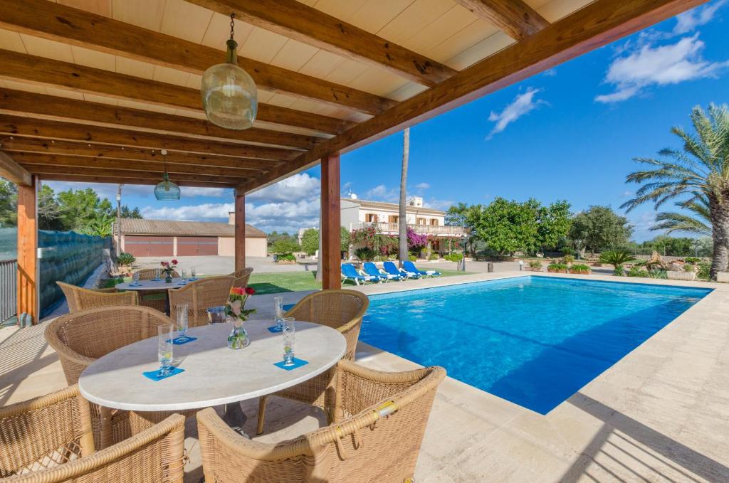 um pátio com uma mesa e cadeiras e uma piscina em YourHouse Sa Garriga Finca Darder villa em Ariany