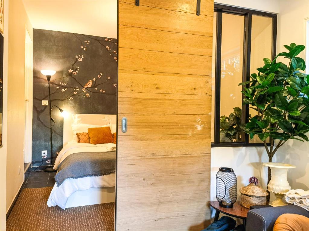 a bedroom with a bed and a wooden wall at Exquisite tiny house with garden and air con - between Paris-Disneyland - 3mins from train station in Noisy-le-Grand