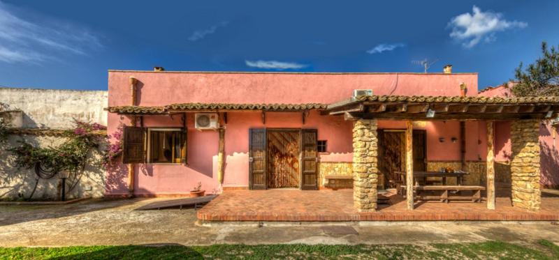 een roze huis met een bank ervoor bij Casale il Pozzo in Sciacca