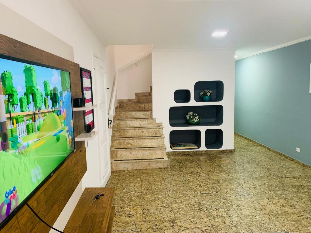 un soggiorno con TV e scala di Sobrado Amplo ( 5 min Hosp. Eintein) a San Paolo