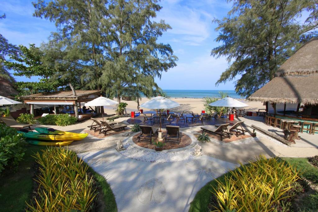 a patio with tables and umbrellas on the beach at Lanta Castaway Beach Resort in Ko Lanta