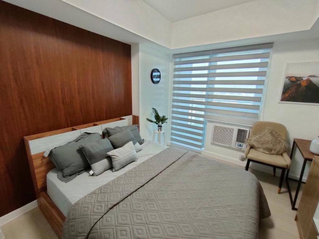 聖弗南多的住宿－The Aces Crib at Azure North Pampanga，一间卧室设有一张大床、一把椅子和窗户。