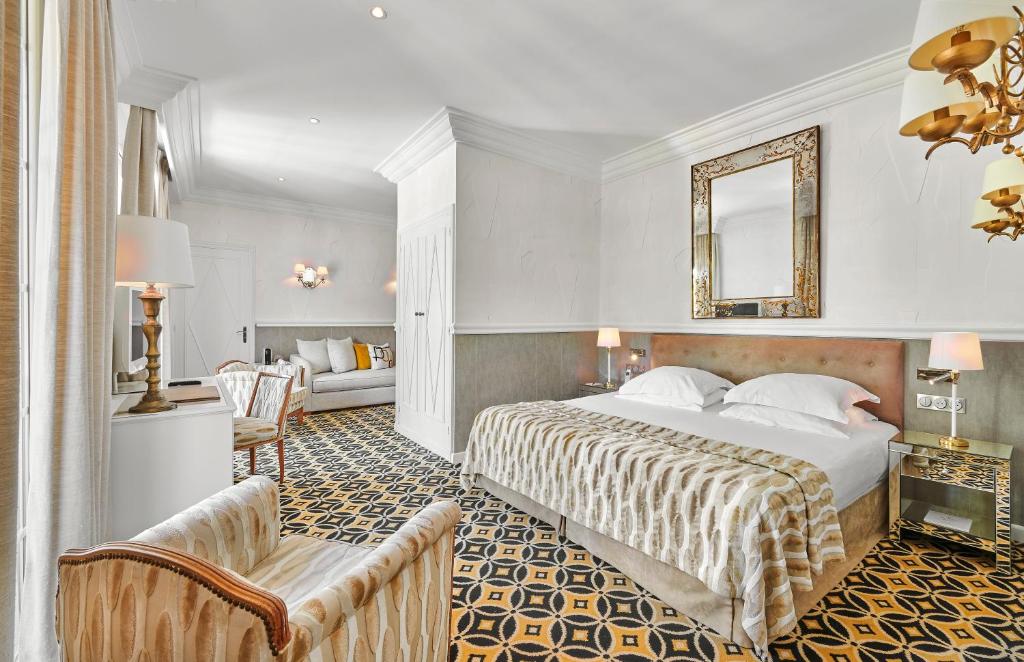 a hotel room with a bed and a living room at Hôtel Belles Rives in Juan-les-Pins