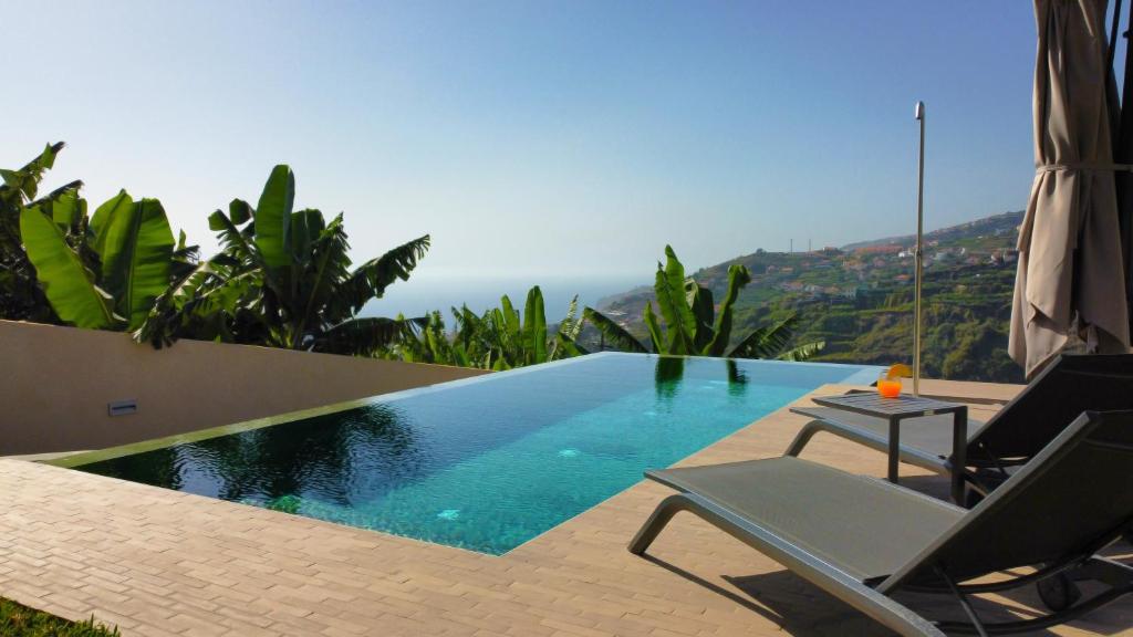 a swimming pool with a chair and a table at Serenity Valley Escape by LovelyStay in Ribeira Brava