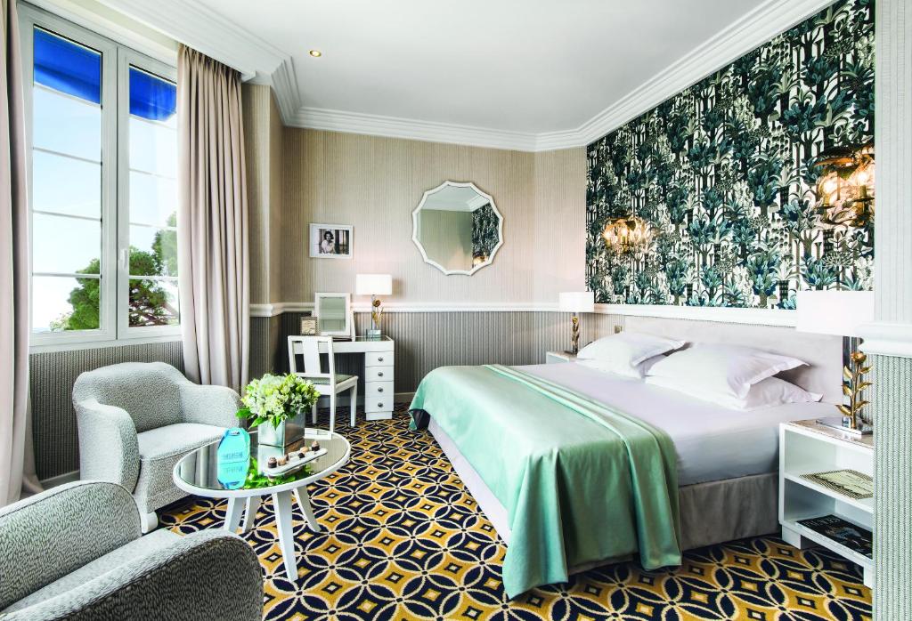 a hotel room with a bed and a chair at Hôtel Belles Rives in Juan-les-Pins