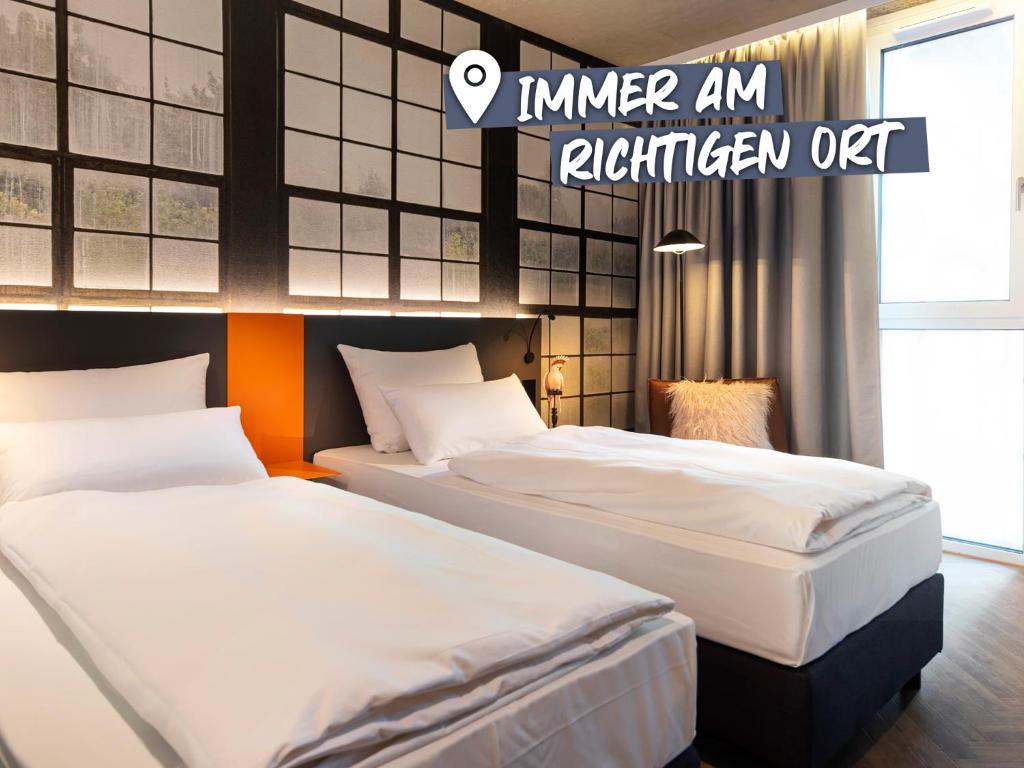 two beds in a hotel room with the words inner an kitchen off at LOGINN Hotel Waiblingen in Waiblingen