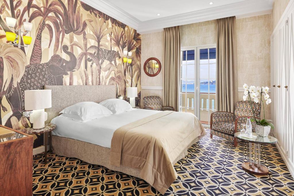 a bedroom with a large bed and a large mural at Hôtel Belles Rives in Juan-les-Pins
