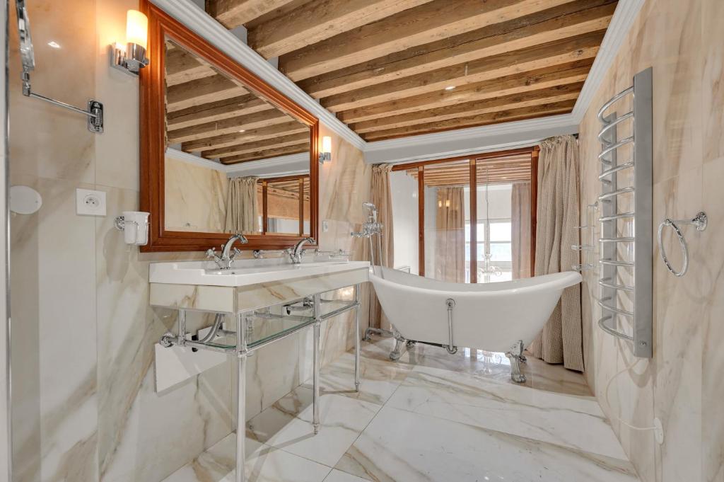 a bathroom with two sinks and a tub and a mirror at Les Relais du Capitole - Appartements d'hôtes in Toulouse