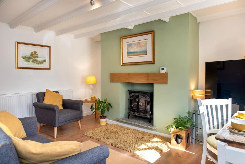 a living room with a fireplace and a blue couch at Country Cottage in quaint Village, sleeps 3 in Bere Alston