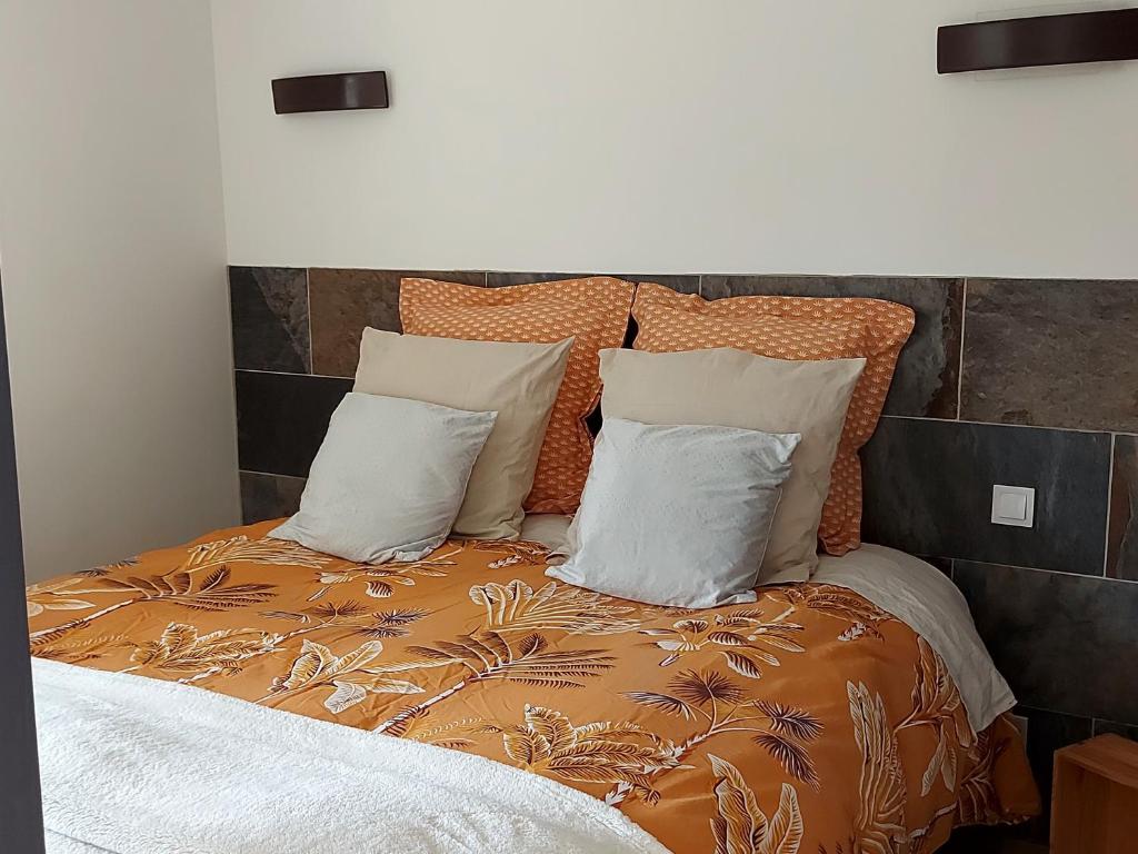 een bed met oranje en witte lakens en kussens bij Villa Maëlla, studio rez-de-jardin in Saint-Michel-la-Forêt