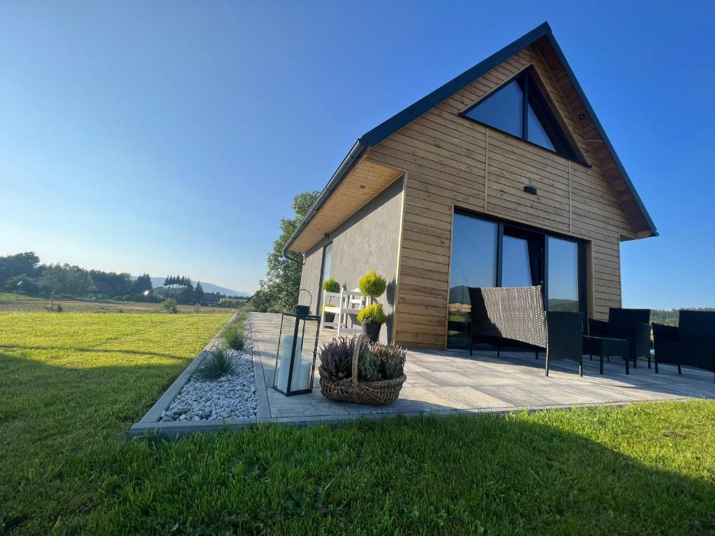 a house with a patio and a grass field at sKLONowane domki pod Czarną Górą in Bystrzyca Kłodzka