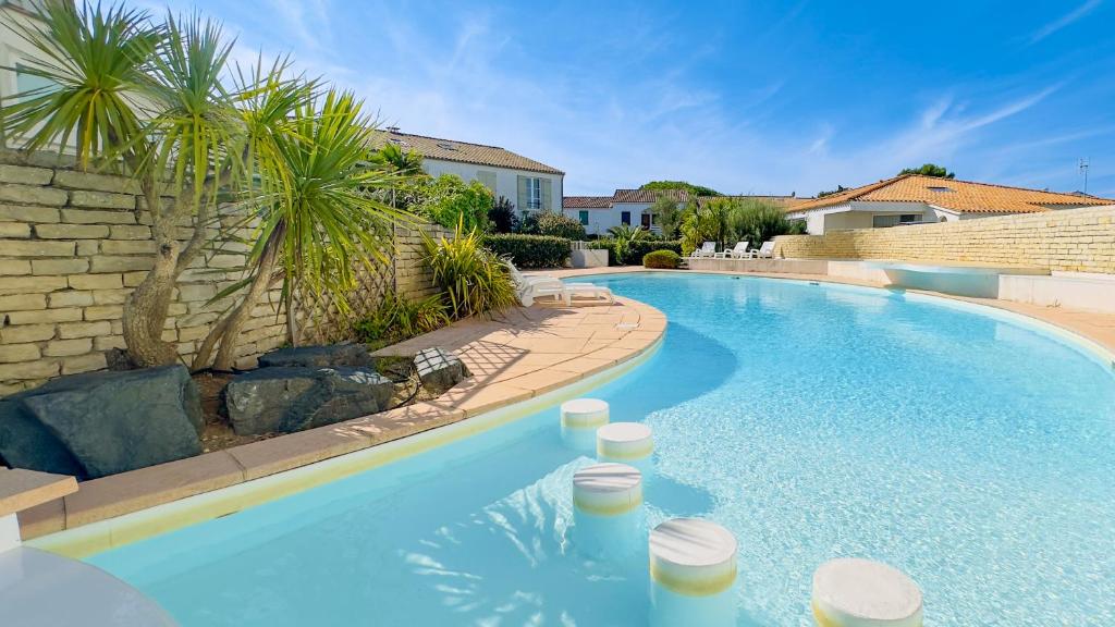 a swimming pool in a yard with a palm tree at Appartement dans résidence avec piscine in La Couarde-sur-Mer