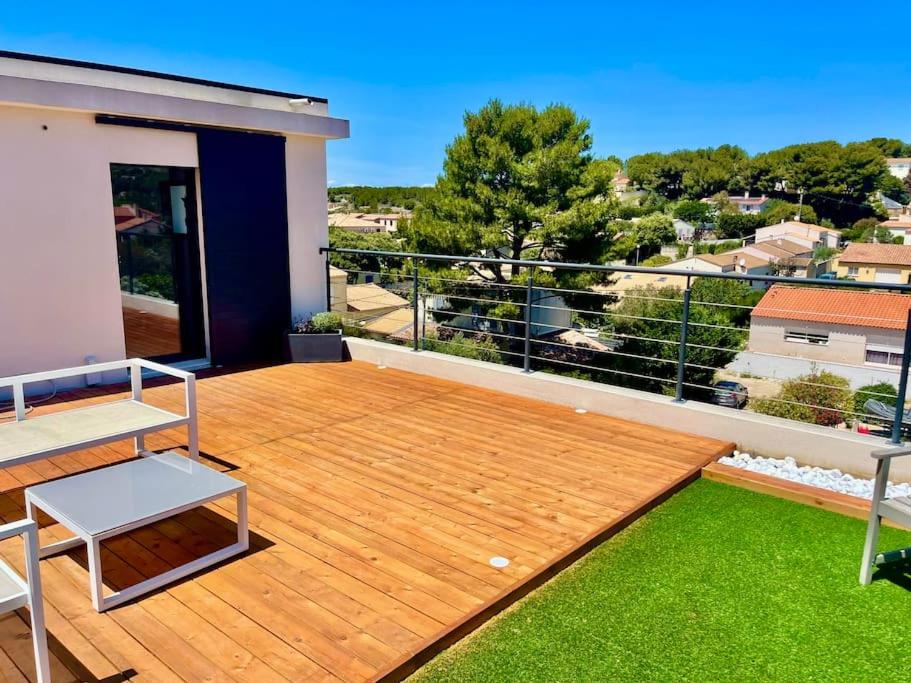 einen Balkon mit einer Holzterrasse mit grünem Gras in der Unterkunft Villa de vacances sur la Côte bleue à la couronne in Martigues