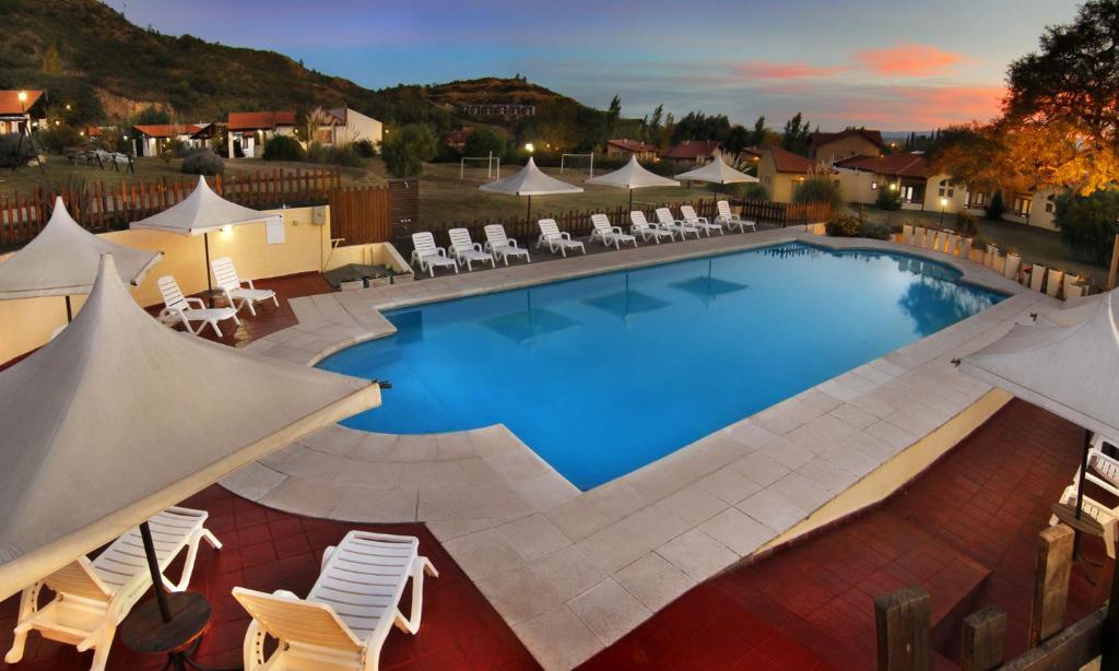 una gran piscina con sillas y sombrillas blancas en Harmonie Hotel De Montaña - Adults only en Villa General Belgrano