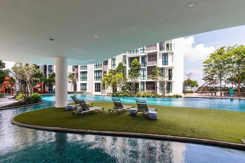 una piscina con sillas y un edificio en H2O Residences Ara Damansara PJ, en Petaling Jaya