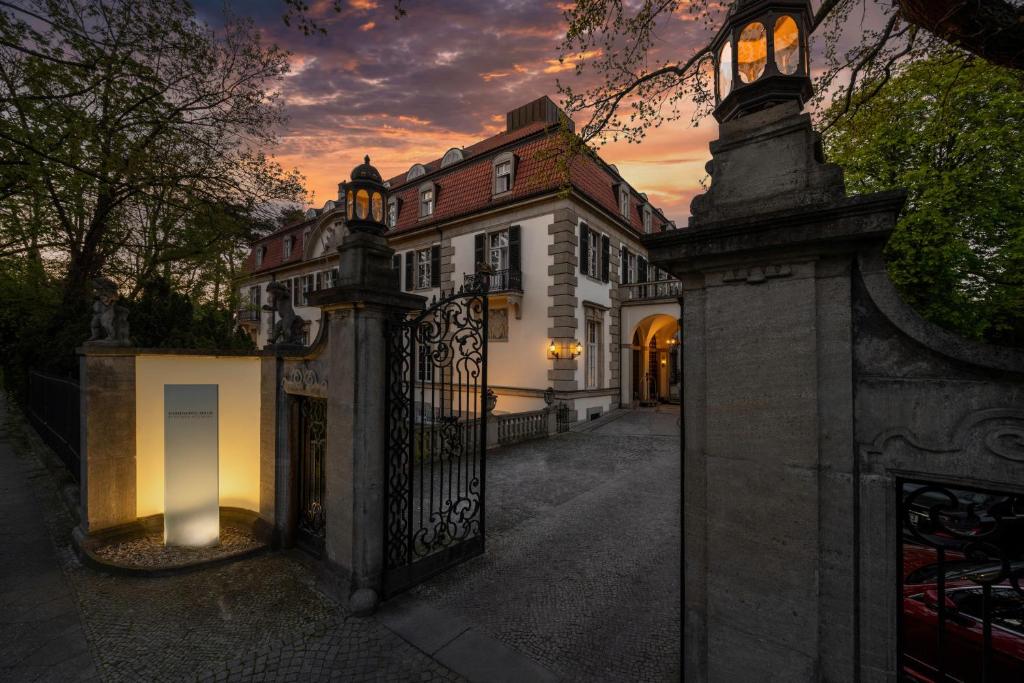 a gate to a house with a sunset in the background at Schlosshotel Berlin by Patrick Hellmann in Berlin