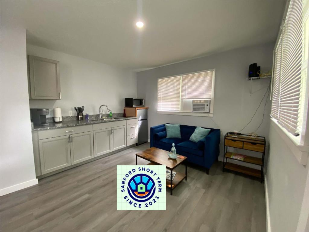 uma sala de estar com um sofá azul e uma cozinha em The Oasis em Sanford