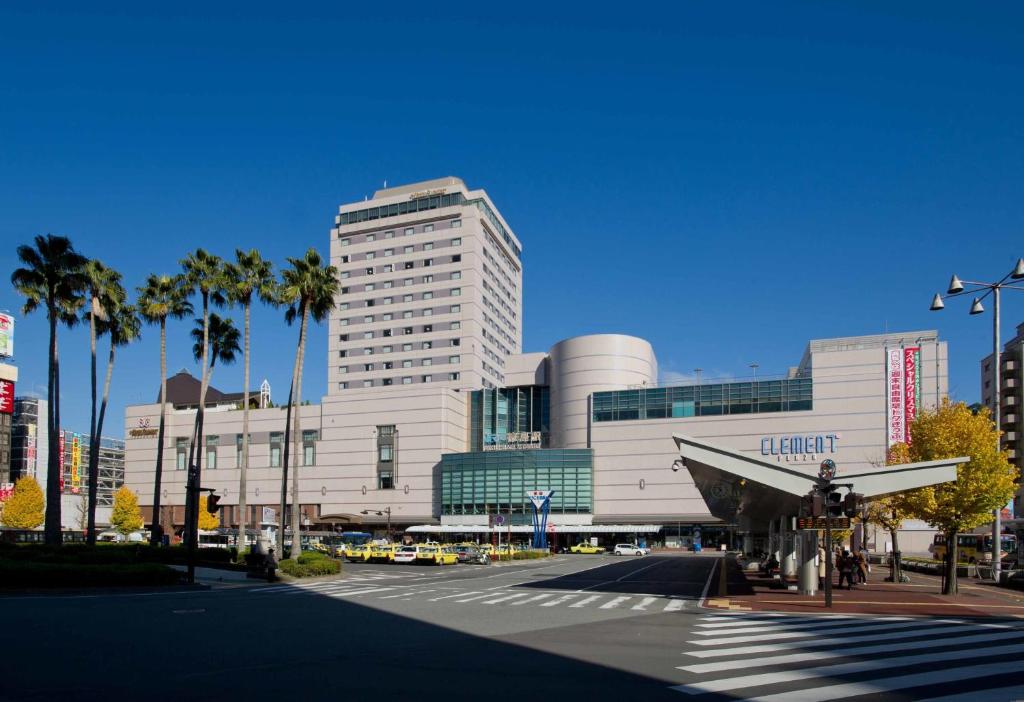 a large building with palm trees in front of a street at JR Hotel Clement Tokushima in Tokushima