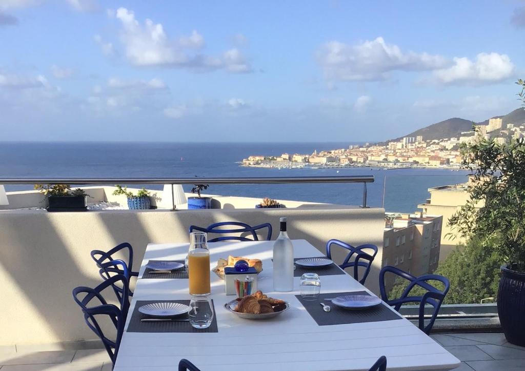 una mesa en un balcón con vistas al océano en Suite avec 2 chambres d'hôtes pour 1 à 4 personnes avec terrasse, vue mer, parking privé, proche port et aéroport, en Ajaccio