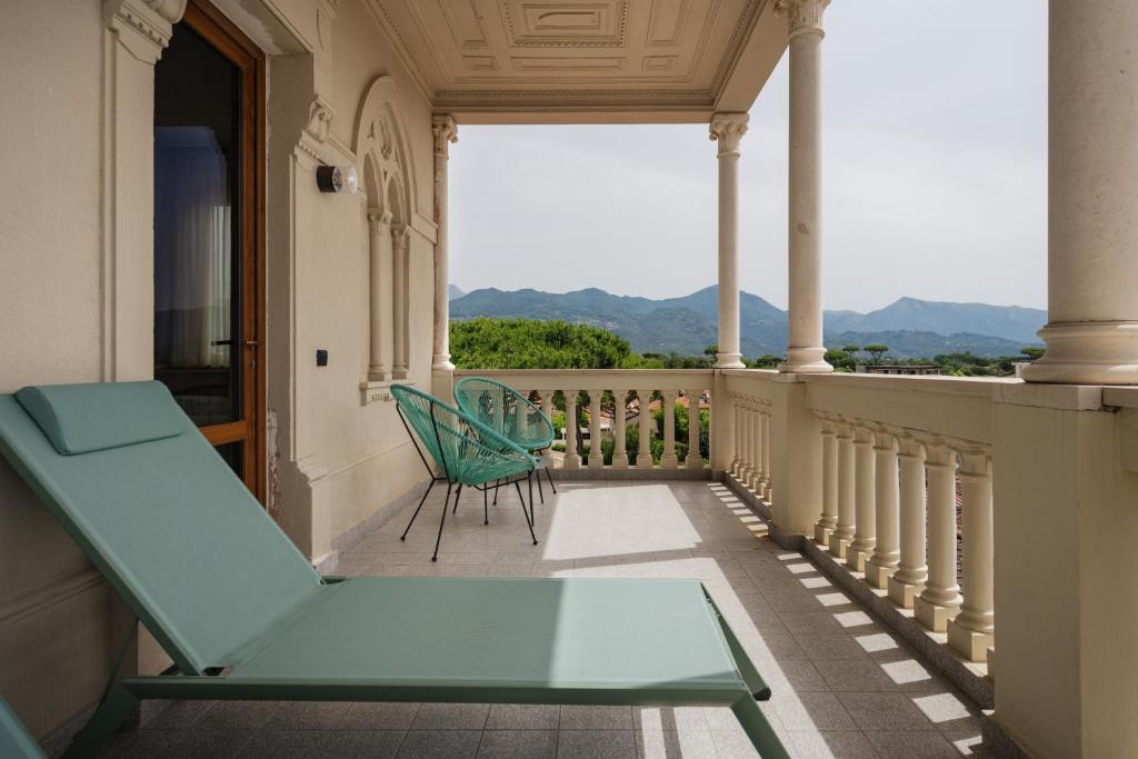 a green chair on a balcony with a view at Re Versiliana Hotel in Marina di Pietrasanta