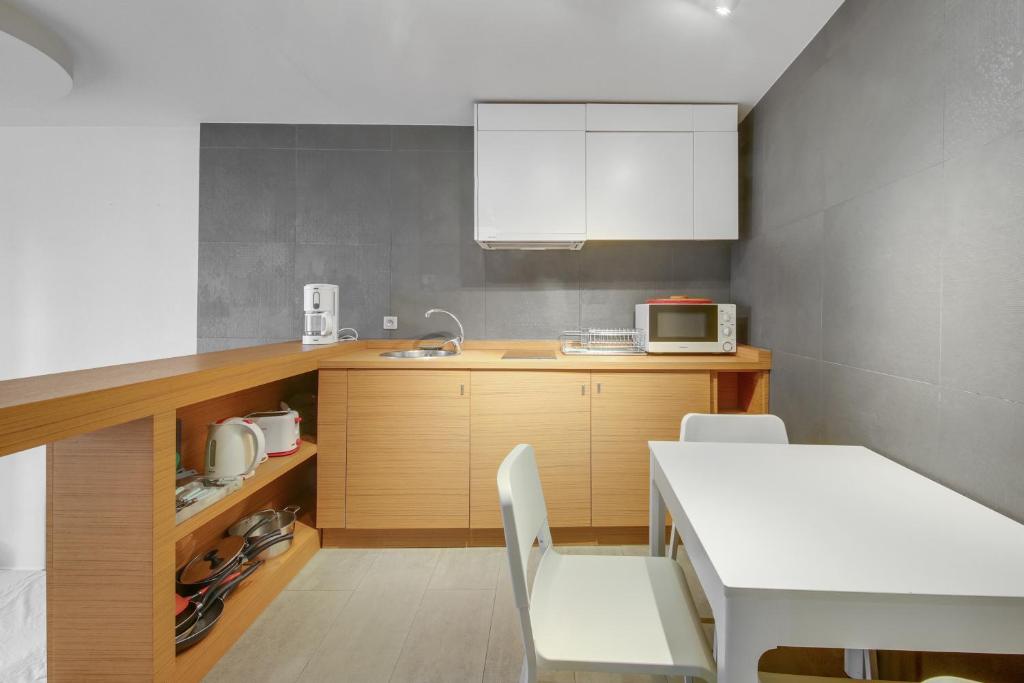 - une cuisine avec une table et une table et des chaises blanches dans l'établissement Élégance confort à l’Odéon by Weekome, à Paris