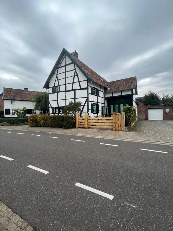 een zwart-wit huis met een hek en een weg bij Het Houwershuuske in Reijmerstok