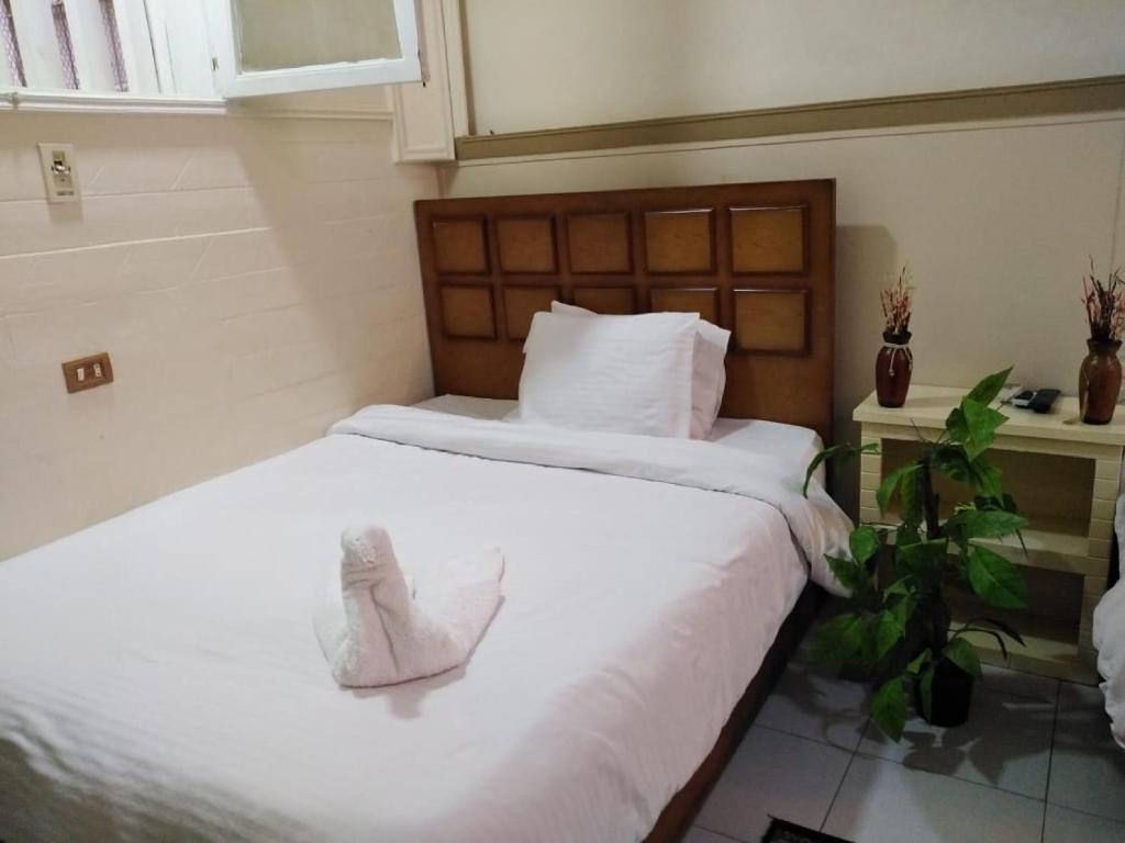 um quarto com duas camas com lençóis brancos e uma planta em Hotel Panorama no Cairo
