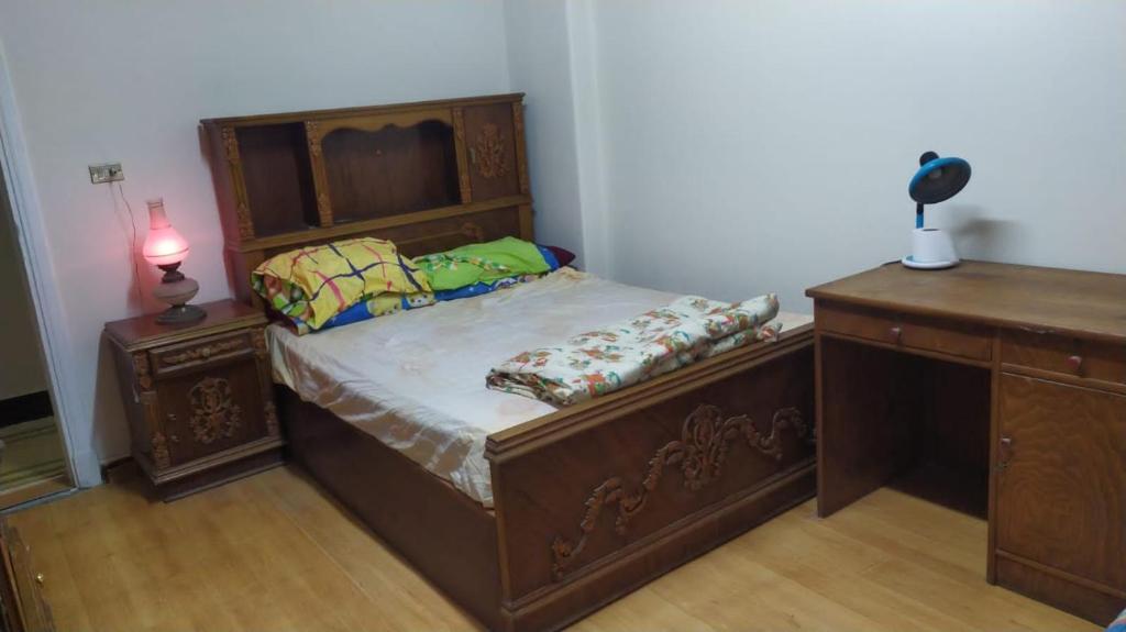 een slaapkamer met een houten bed en een bureau bij Ismailia - Elnouras compound in Ismailia