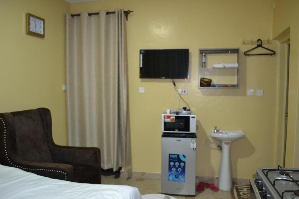 a room with a bed and a microwave and a sink at ROSEVIEW in Kiambu