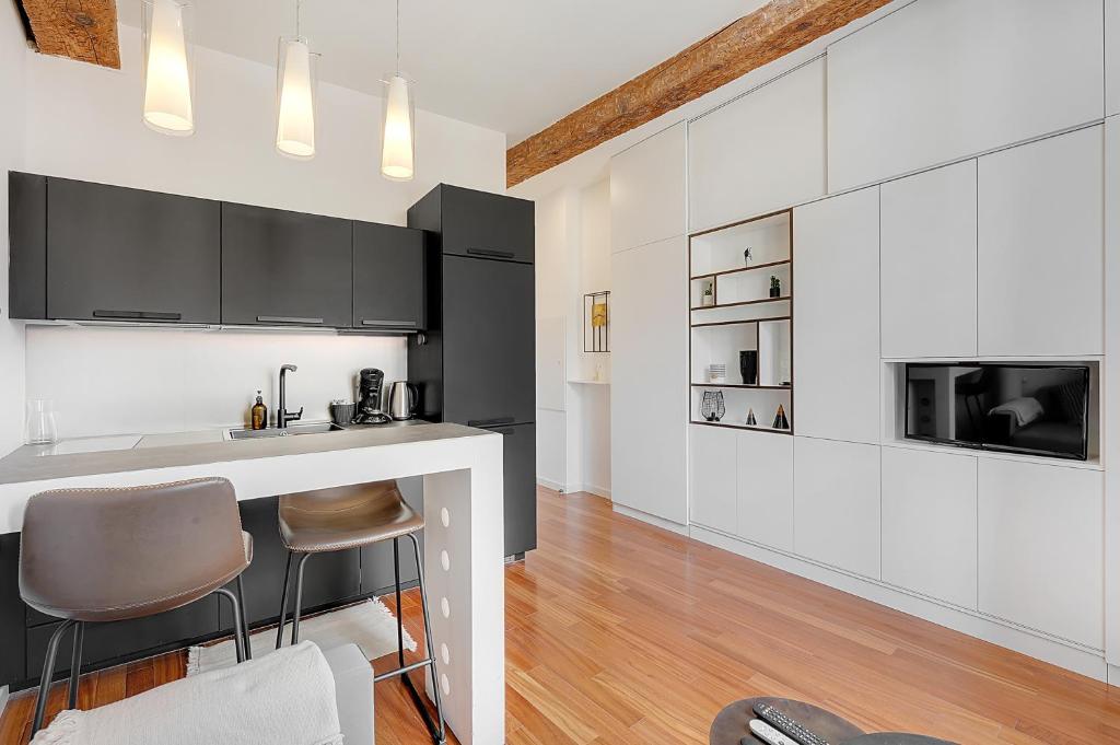 a kitchen with white cabinets and a bar with a microwave at Les Relais du Capitole - Appartements d'hôtes in Toulouse