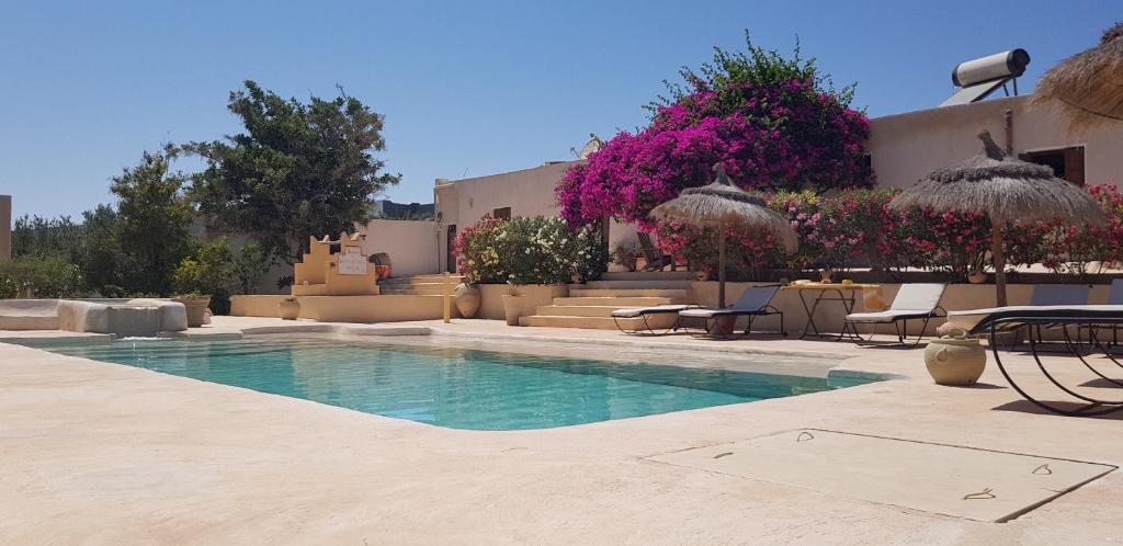 una piscina con mesas, sillas y flores en Menzel Caja en Aghīr