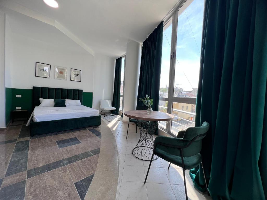 a bedroom with a bed and a table and window at Cactus Apartments in Durrës