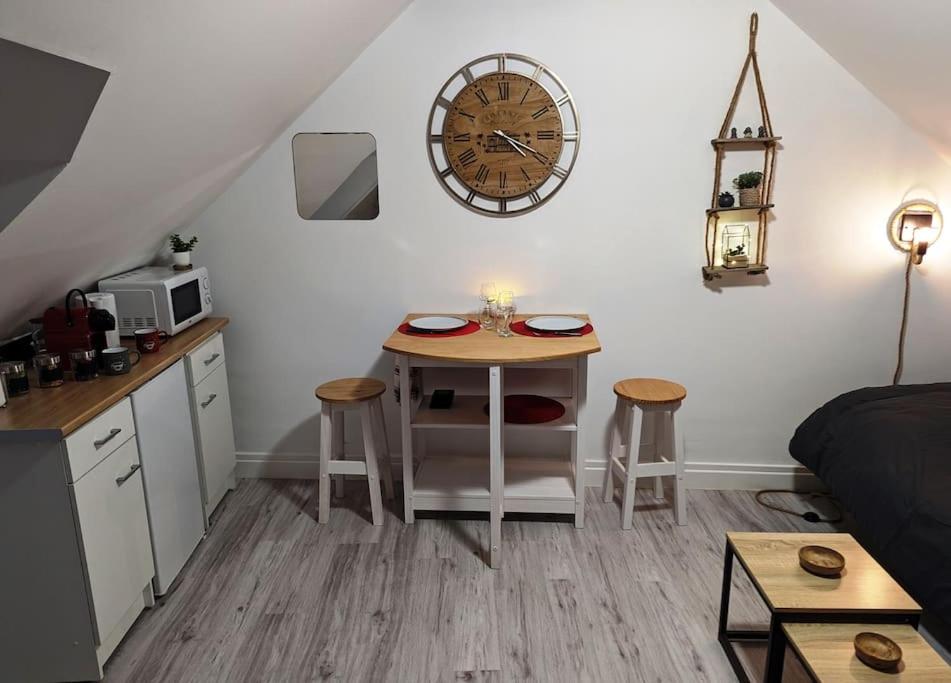 une petite cuisine avec une table et une horloge murale dans l'établissement Studio calme et cosy, à Caen