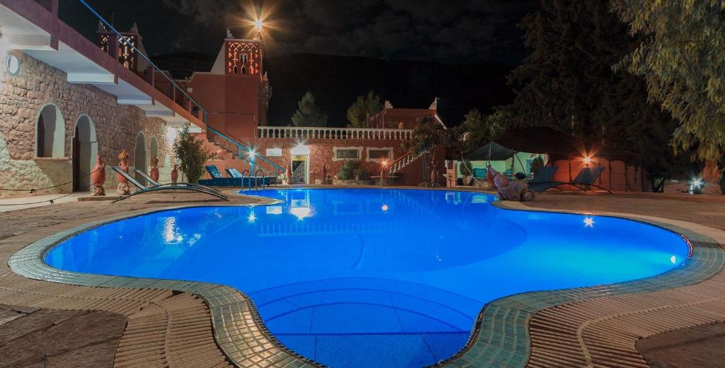 a large blue swimming pool at night at Hotel Baddou in Tamtetoucht