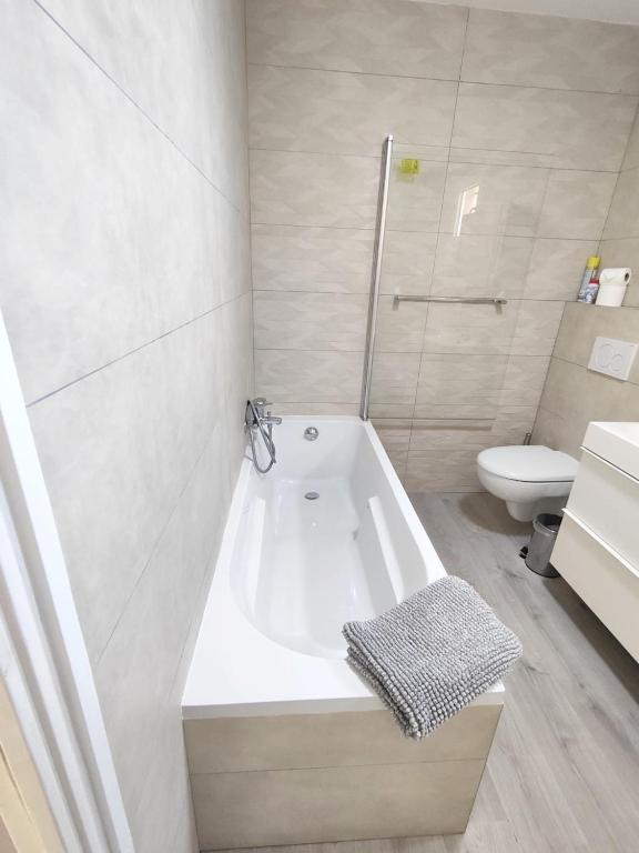 a white bathroom with a tub and a toilet at Maison de 2 chambres avec vue sur la mer jardin clos et wifi a Sete in Sète