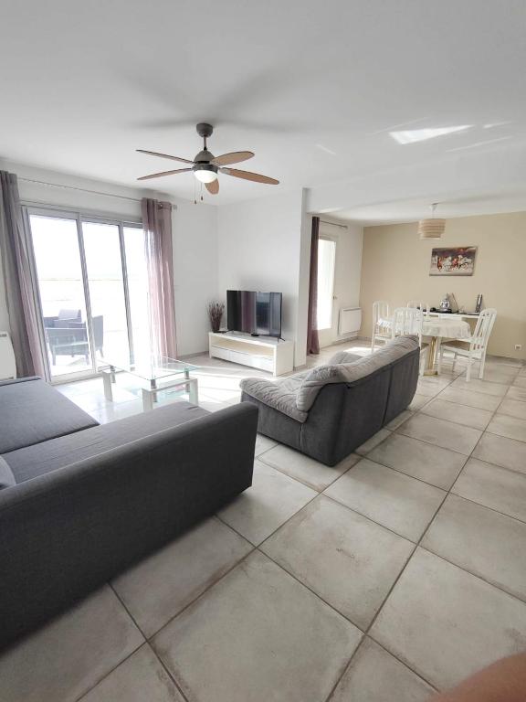 a living room with couches and a table with a television at Maison de 2 chambres avec vue sur la mer jardin clos et wifi a Sete in Sète