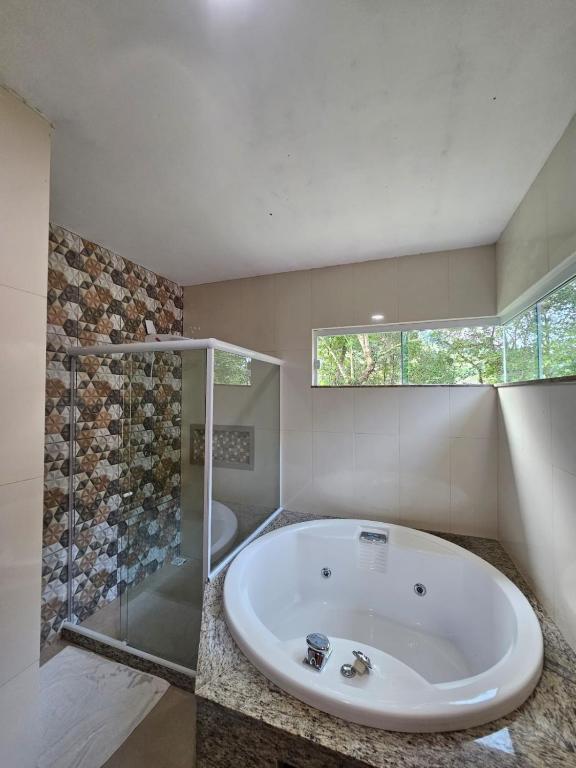 uma ampla casa de banho com uma banheira e um chuveiro em vidro. em Hotel Pousada Bambuzal em Sana