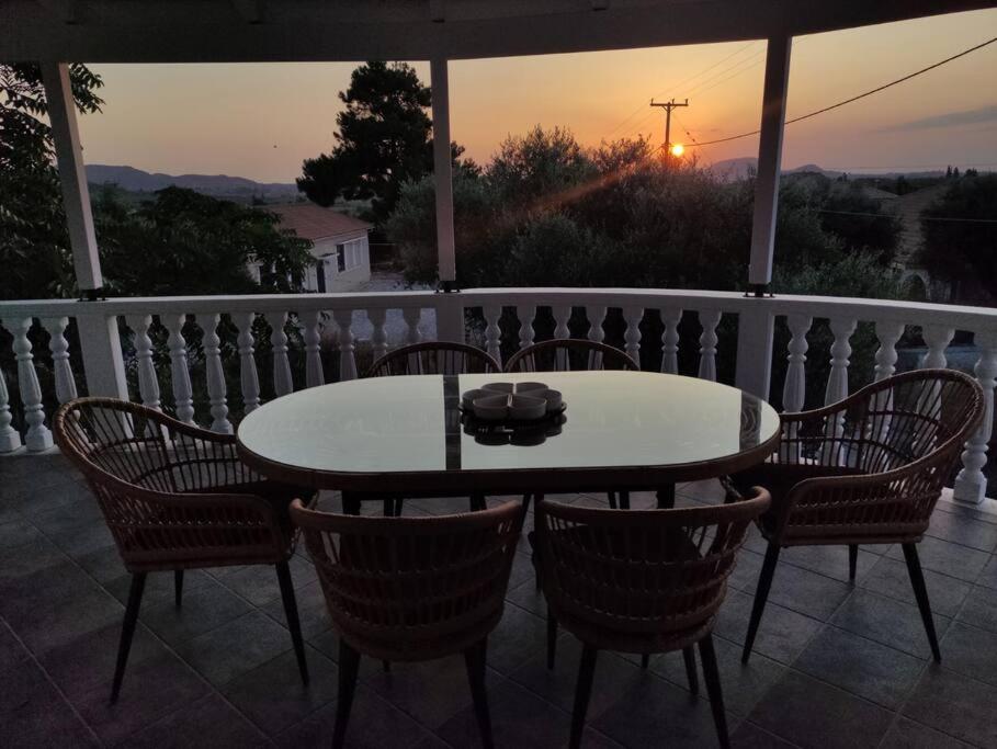 una mesa y sillas en un balcón con puesta de sol en Ευρύχωρη και φωτεινή κατοικία στη Ζάκυνθο en Makhairádhon